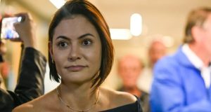 A ex-primeira-dama Michelle Bolsonaro no canto esquerdo da foto, com expressão de espanto