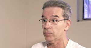 ex-senador Luiz Estevão de óculos de grau e camiseta branca, com expressão de espanto, sem olhar para a câmera