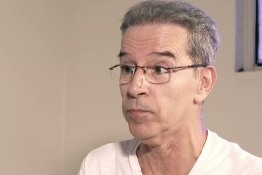 ex-senador Luiz Estevão de óculos de grau e camiseta branca, com expressão de espanto, sem olhar para a câmera