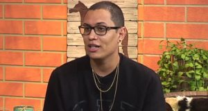 O dono da página “Choquei”, Raphael Sousa Oliveira, de moletom preto e óculos de grau, falando e olhando pro lado, sério