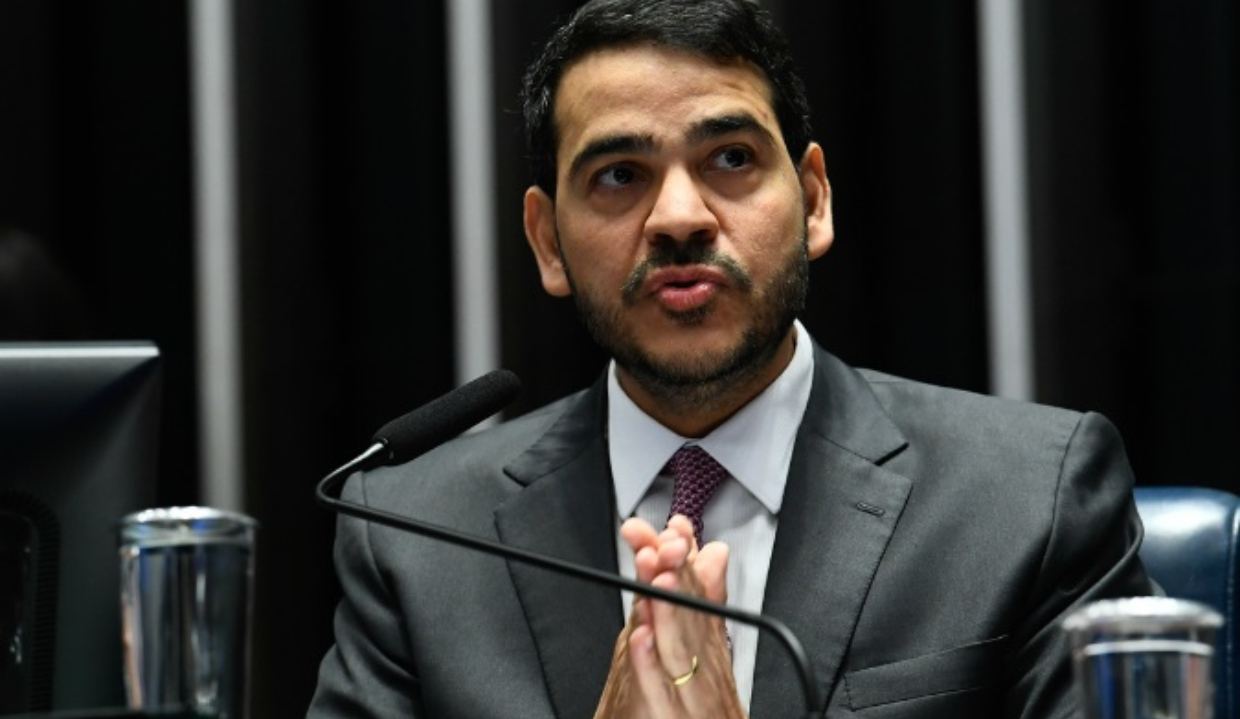 Jorge Messias com expressão pensativa, olhando para o lado, com as mãos unidas