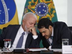 O presidente Luiz Inácio Lula da Silva (PT) e Jorge Messias, da AGU, conversando ao pé do ouvido, sentados lado a lado