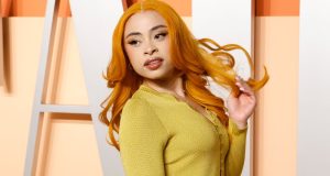 A rapper Ice Spice de cabelo solto e roupa amarela, fazendo carão