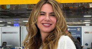 Luciana Gimenez de branco, de cabelo solto, sorrindo para a câmera