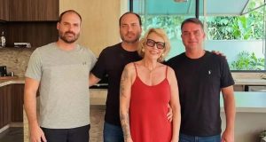 Rogéria Bolsonaro com os filhos Eduardo, Carlos e Flávio, em pé, lado a lado, sorrindo para a câmera