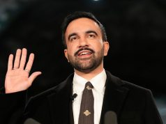 O prefeito de Nova York, Zohran Mamdani, sorrindo e acenando, de roupa social preta e branca