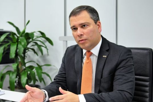 O ex-presidente do Banco de Brasília (BRB), Paulo Henrique Costa, sentado, falando e gesticulando, sério