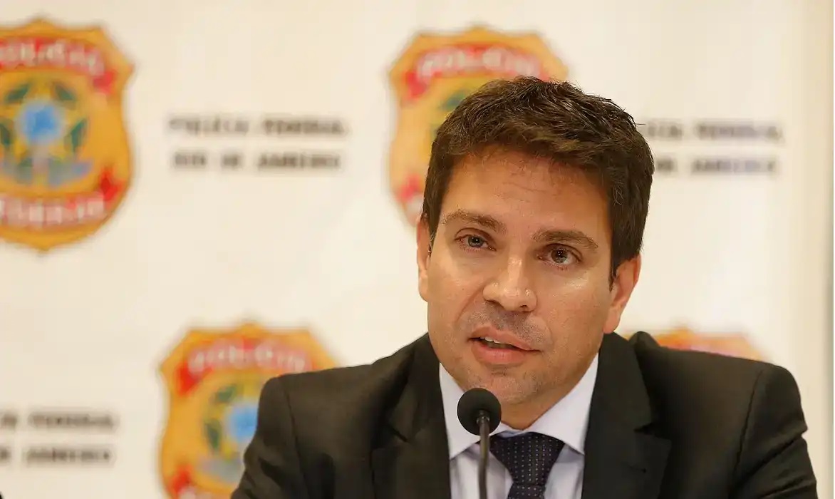 ex-deputado federal Alexandre Ramagem sério, falando, com painel da PF ao fundo