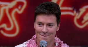 Rodrigo Faro sorrindo, segurando microfone, sem olhar para a câmera