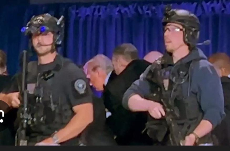 Donald Trump sendo retirado as pressas pelos serviços secretos após tiroteio em jantar com a imprensa. Texto de Moisés Mendes comenta sobre a entrevista do presidente ao 60 minutes no dia seguinte.