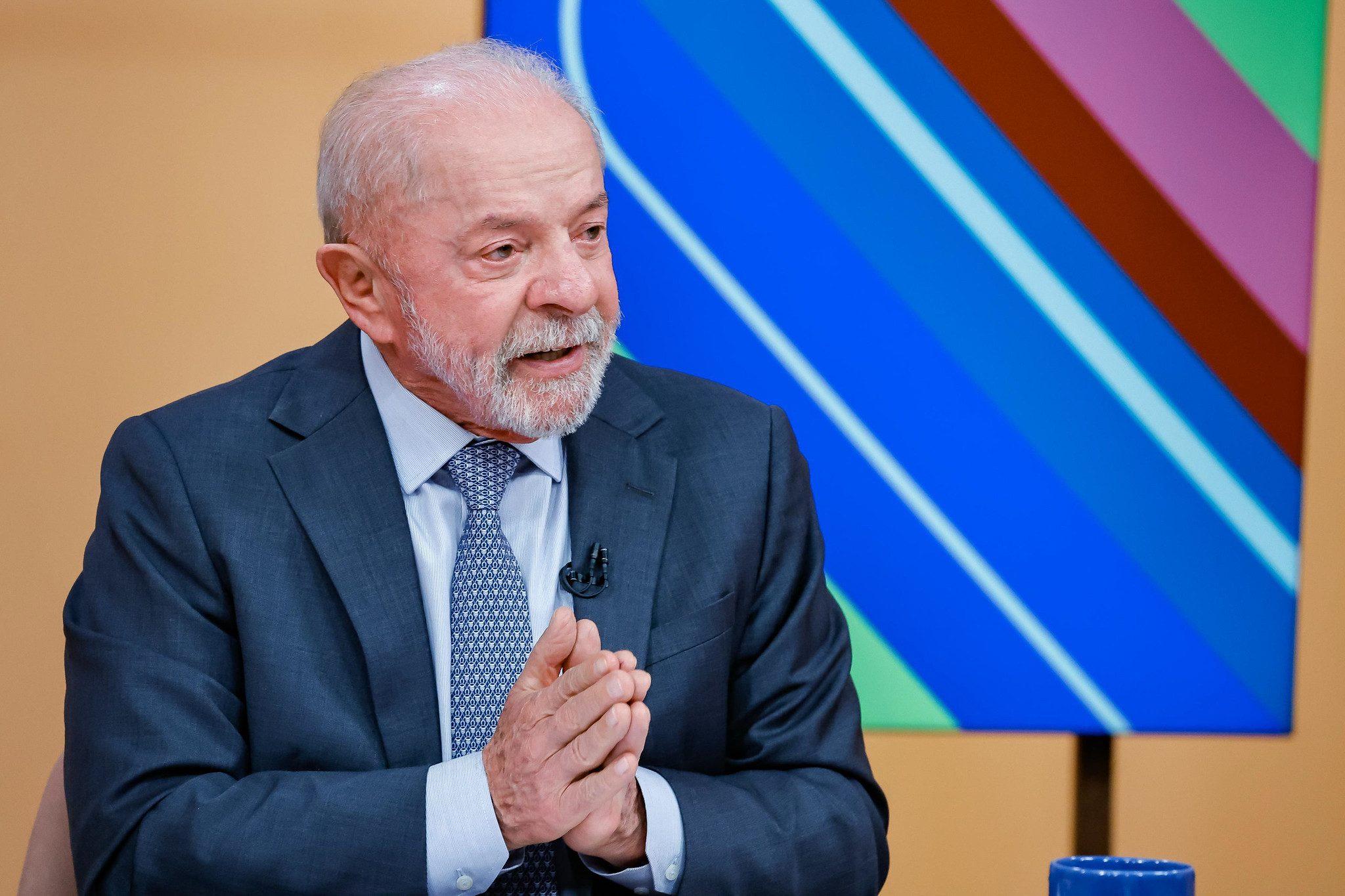 Presidente da República, Luiz Inácio Lula da Silva no canto esquerdo de foto, falando e gesticulando, sério