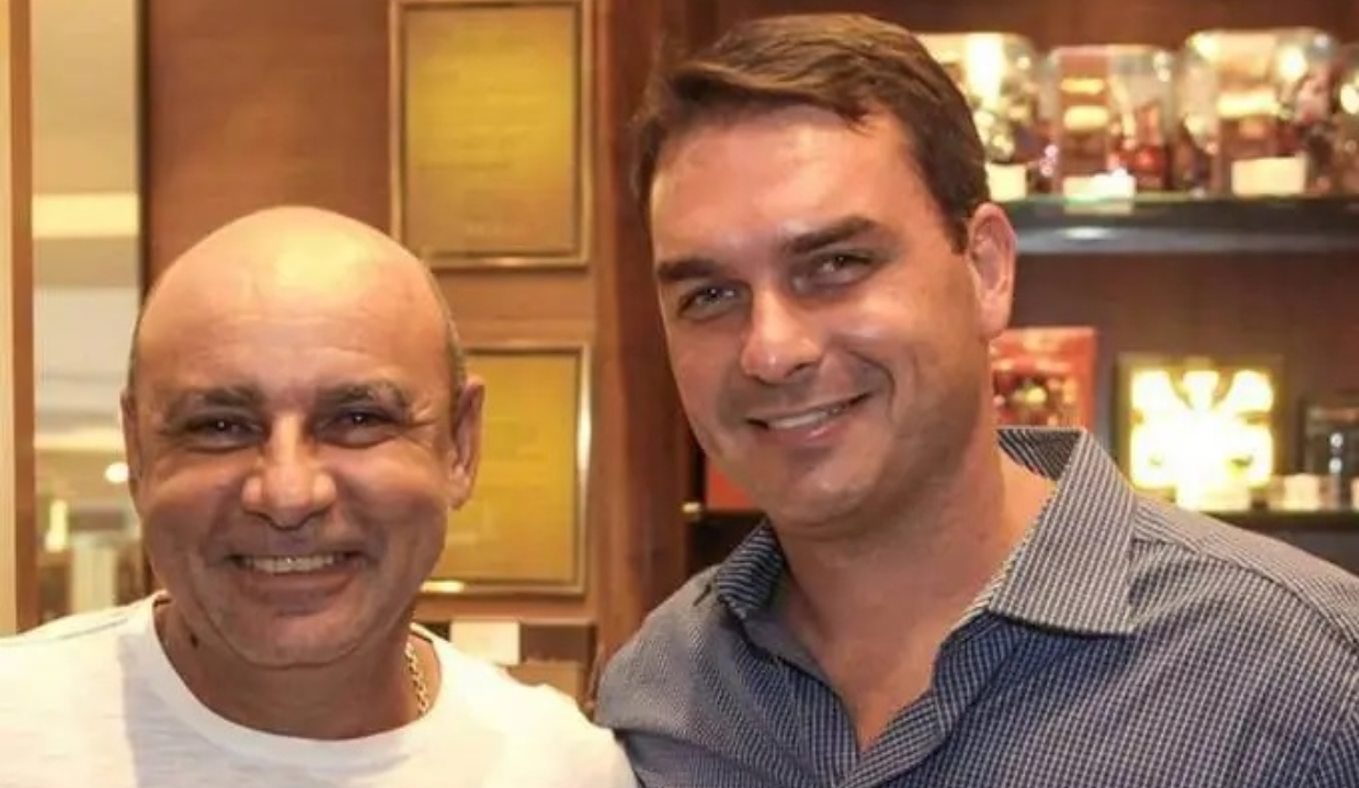 O policial militar da reserva Fabrício Queiroz e o senador Flávio Bolsonaro (PL-RJ) sorrindo lado a lado