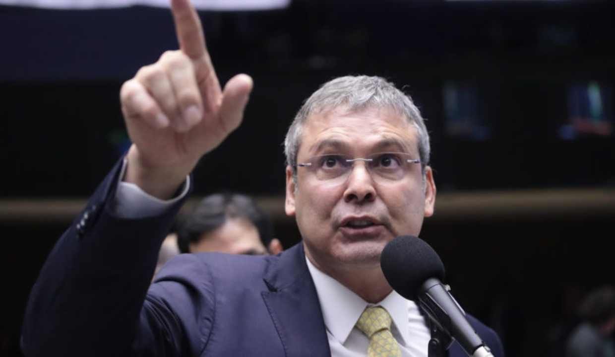 O deputado federal Lindbergh Farias falando e apontando pra frente, de óculos escuros, sério