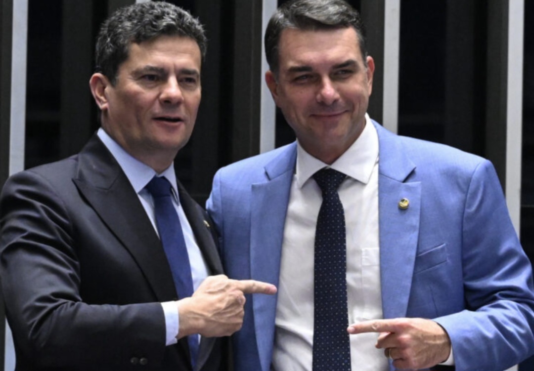 Sergio Moro e Flávio Bolsonaro em pé, lado a lado, sorrindo