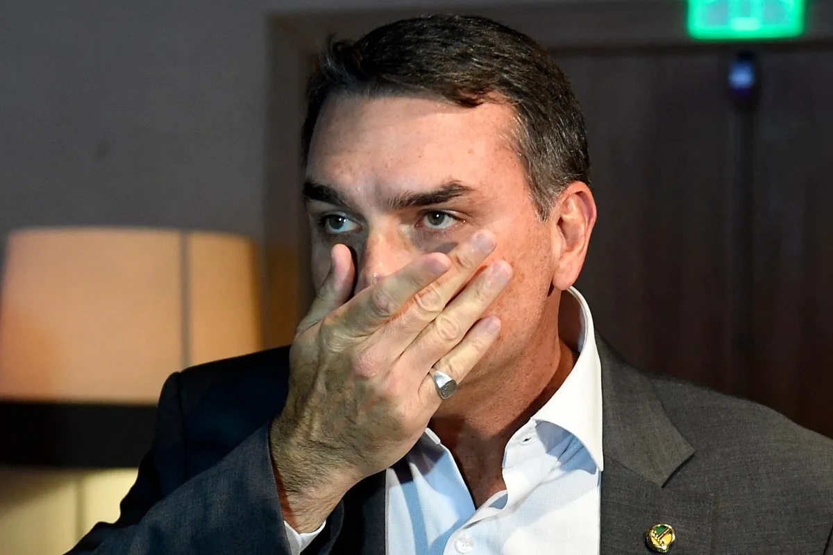senador Flávio Bolsonaro (PL) com uma das mãos no rosto, sério