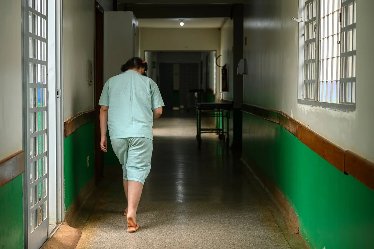 Diretor do hospital caminha ao lado da adolescente em corredor da unidade