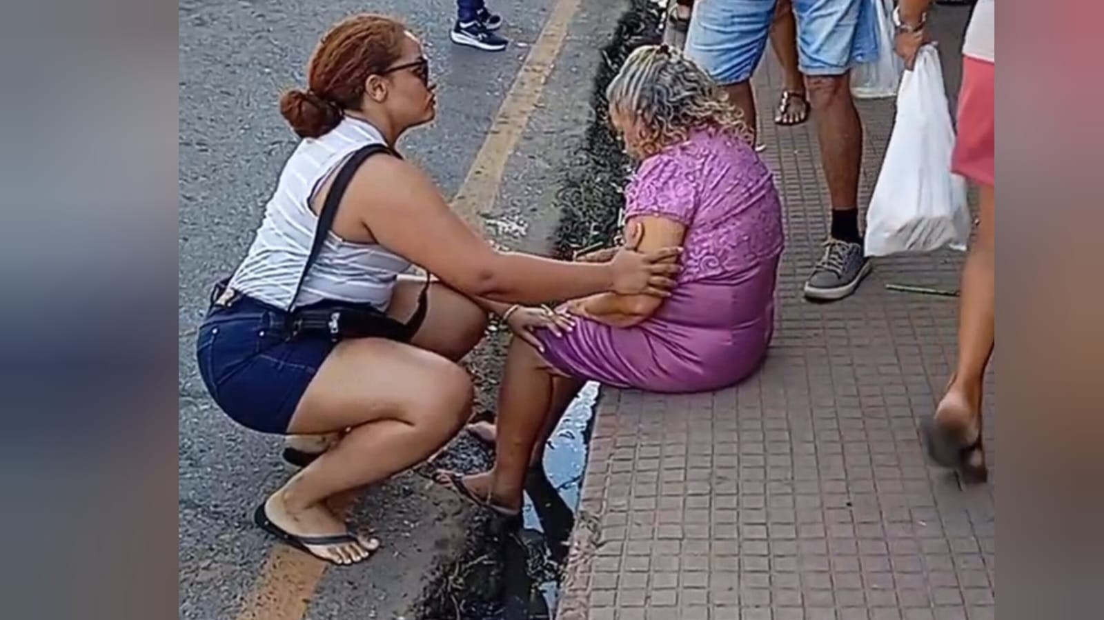 Passageira idosa sentada na sarjeta após queda de ônibus em Santarém