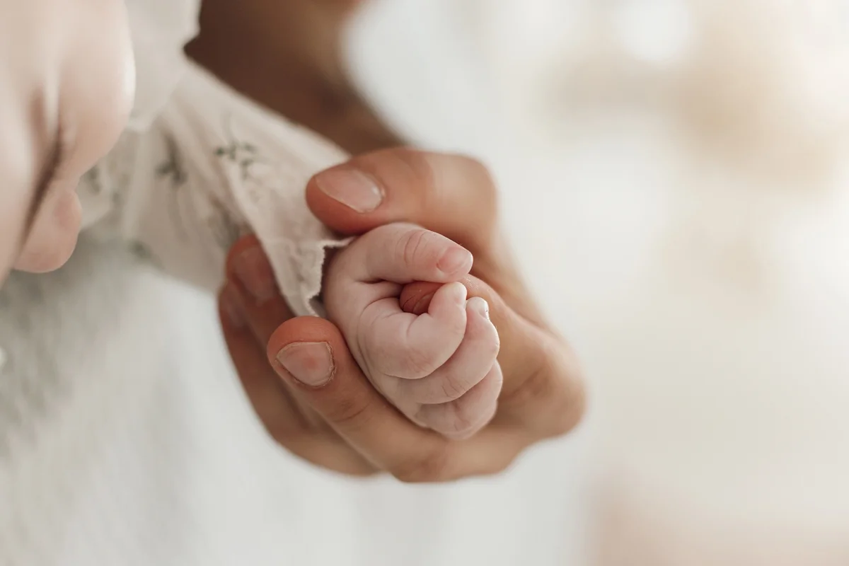 Mãe segura a mão de um bebê