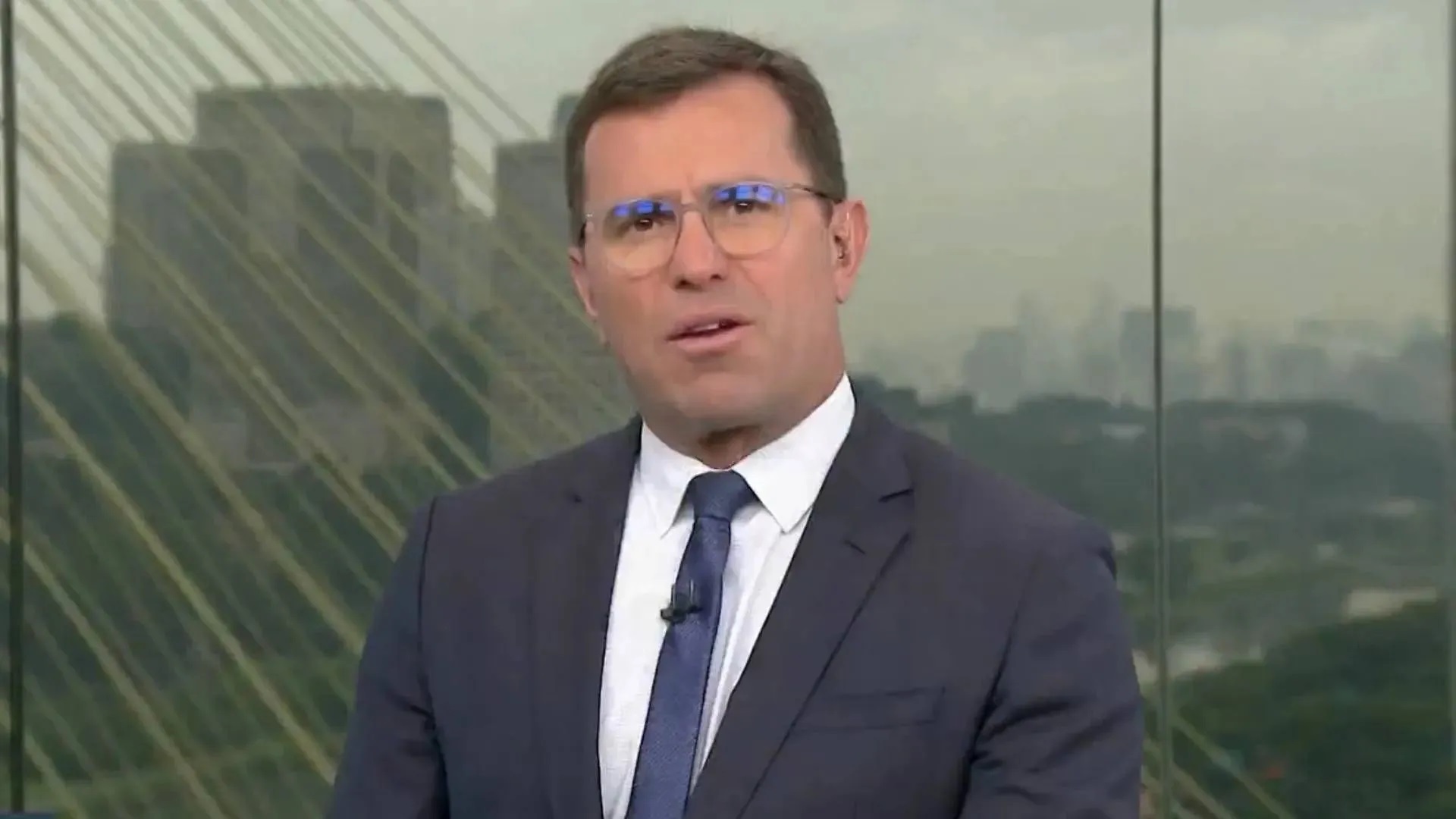 jornalista Rodrigo Bocardi sério, falando para a câmera, de óculos