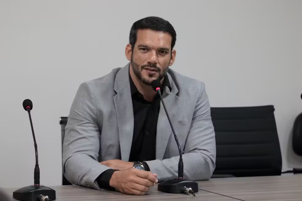 Samir Xaud, sério, sentado, de roupa social cinza e preta
