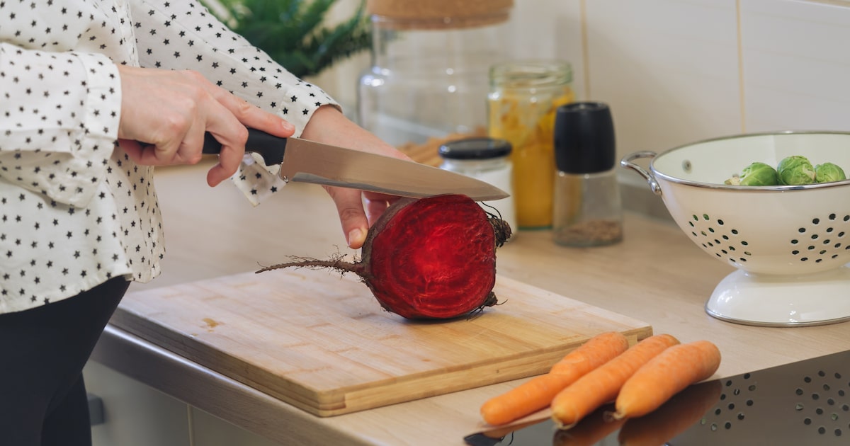 Mulher cortando beterraba vermelha na cozinha