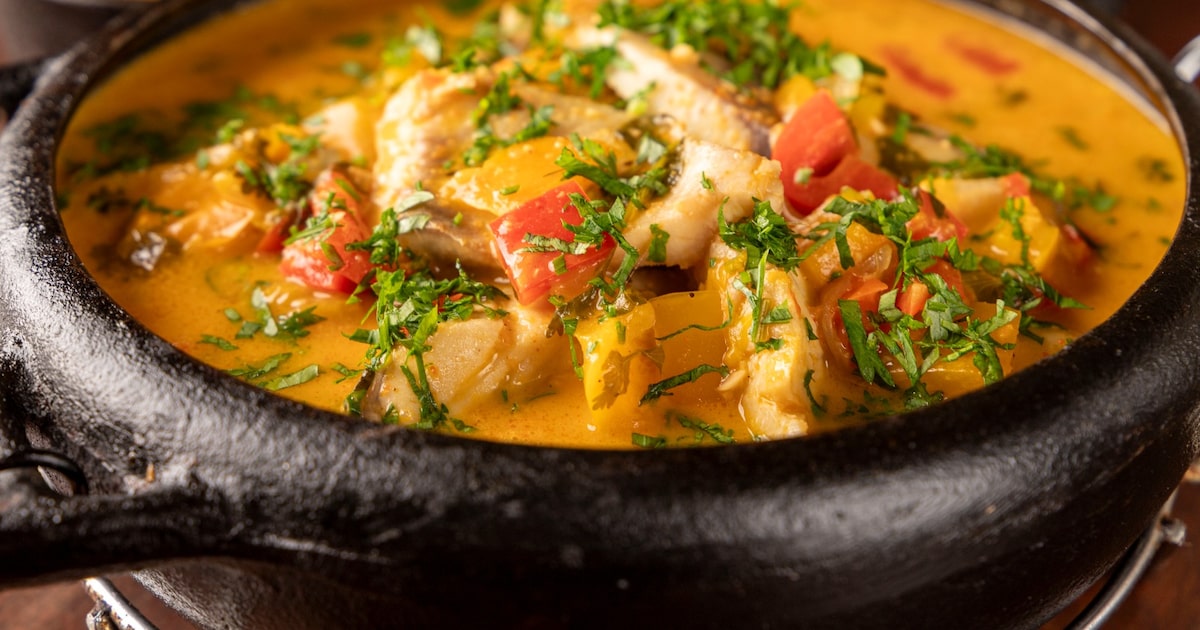 Moqueca em panela com caldo alaranjado e ervas frescas