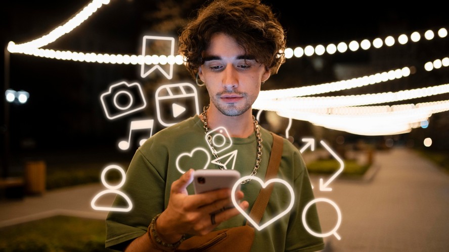 Pessoa usando celular diante de ícones de redes sociais
