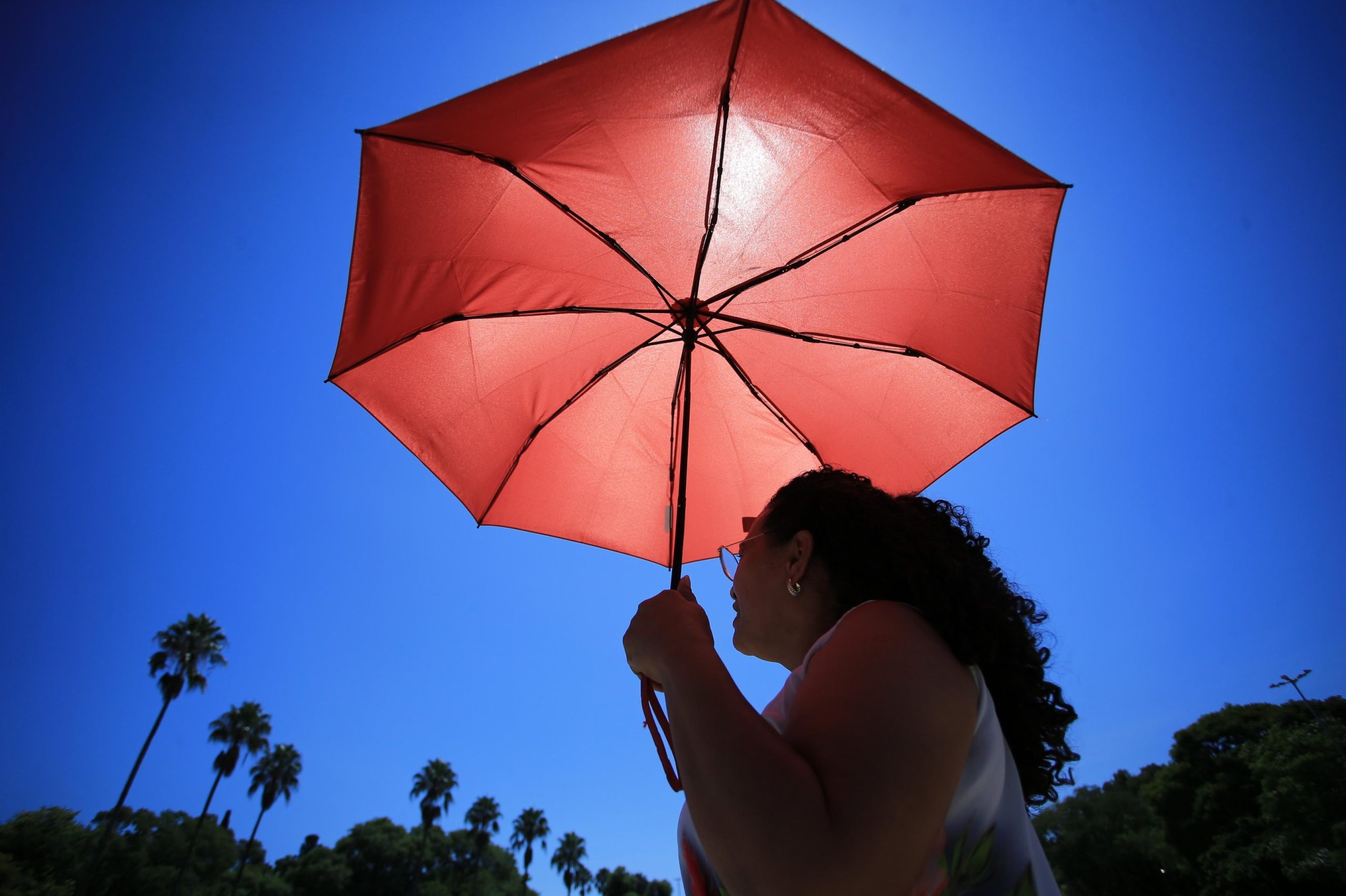 Mulher usando sombrinha para se proteger do sol em Porto Alegre