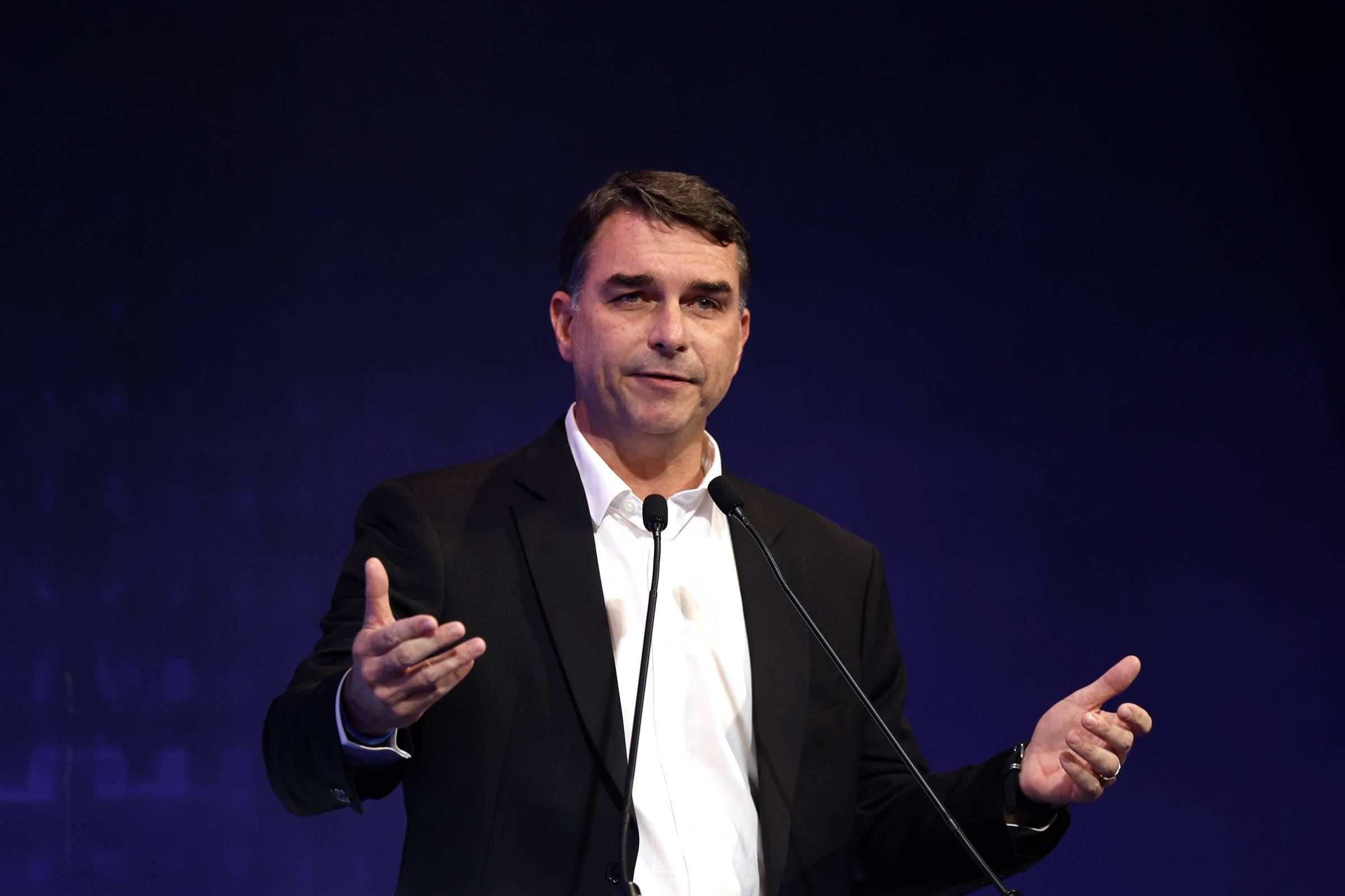 Flávio Bolsonaro falando ao microfone em debate da CNI