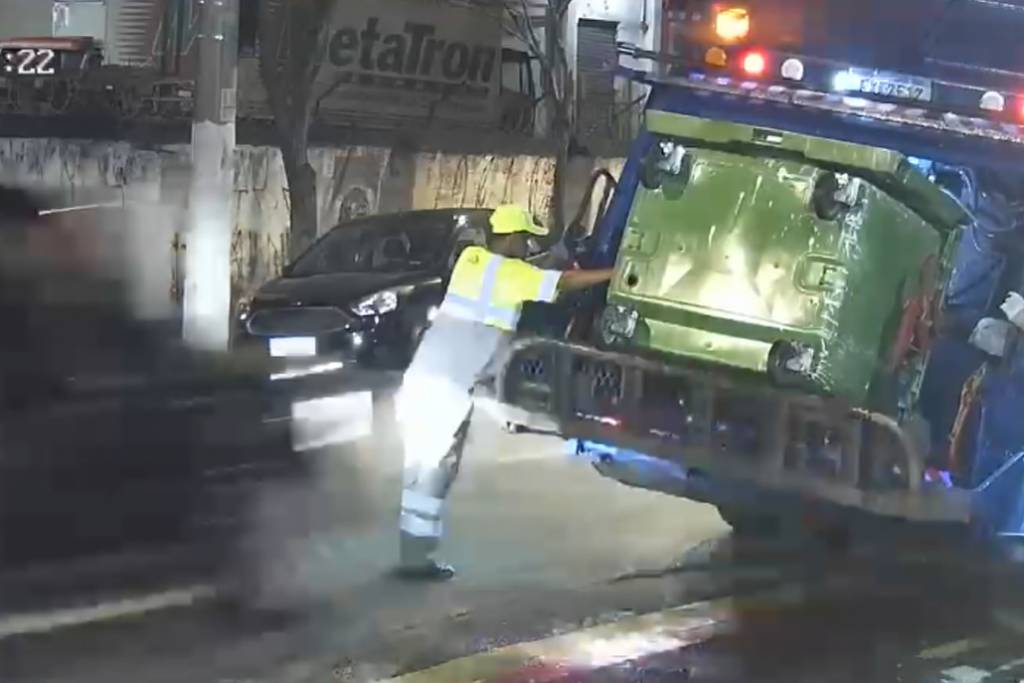 Veículo próximo a caminhão de coleta em rua de São Paulo