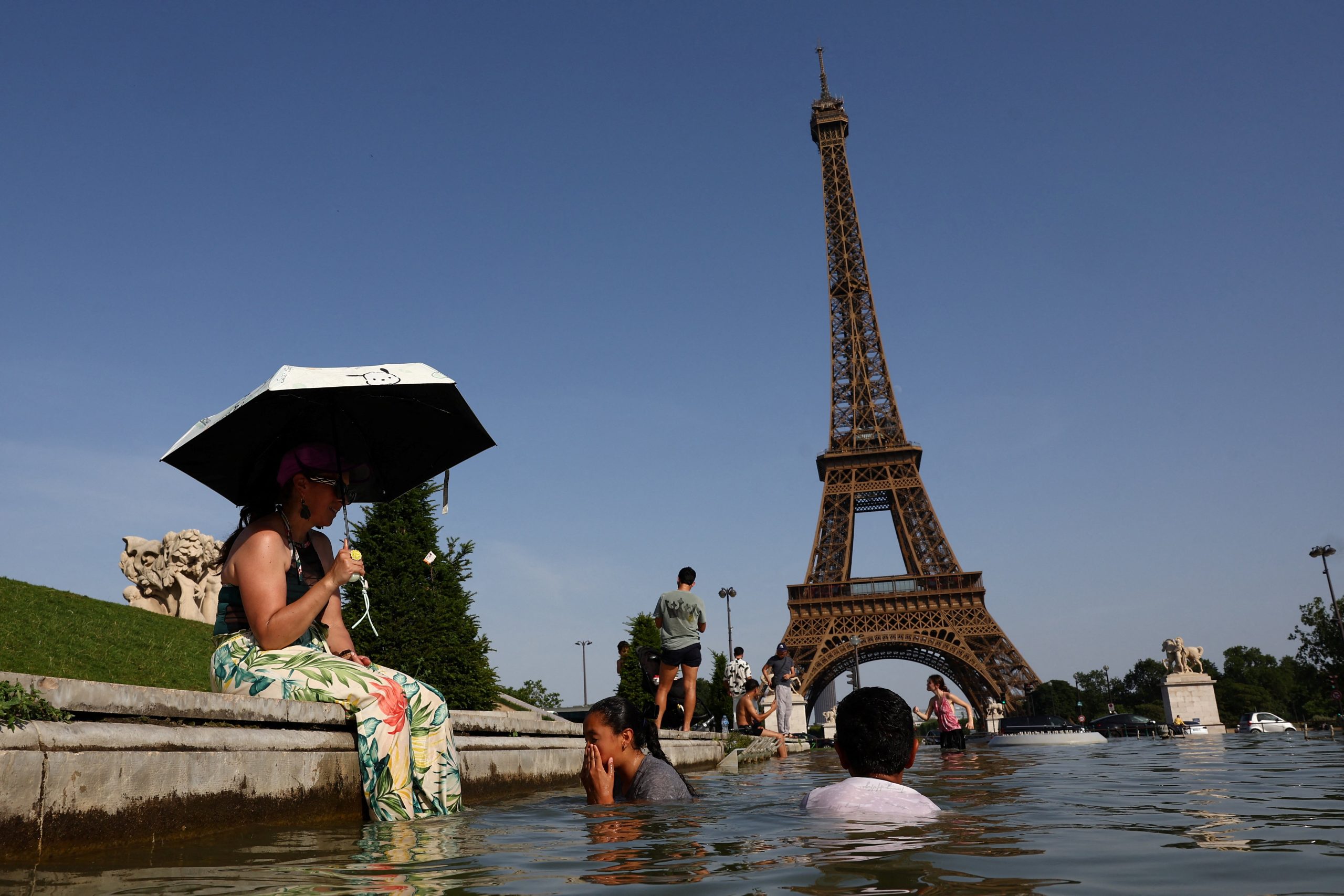 Pessoas se refrescam na fonte do Trocadéro diante da Torre Eiffel durante onda de calor em Paris