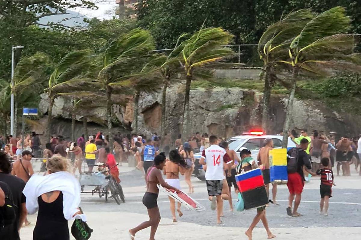 Banhistas se abrigam do vento forte na praia do Arpoador, no Rio de Janeiro