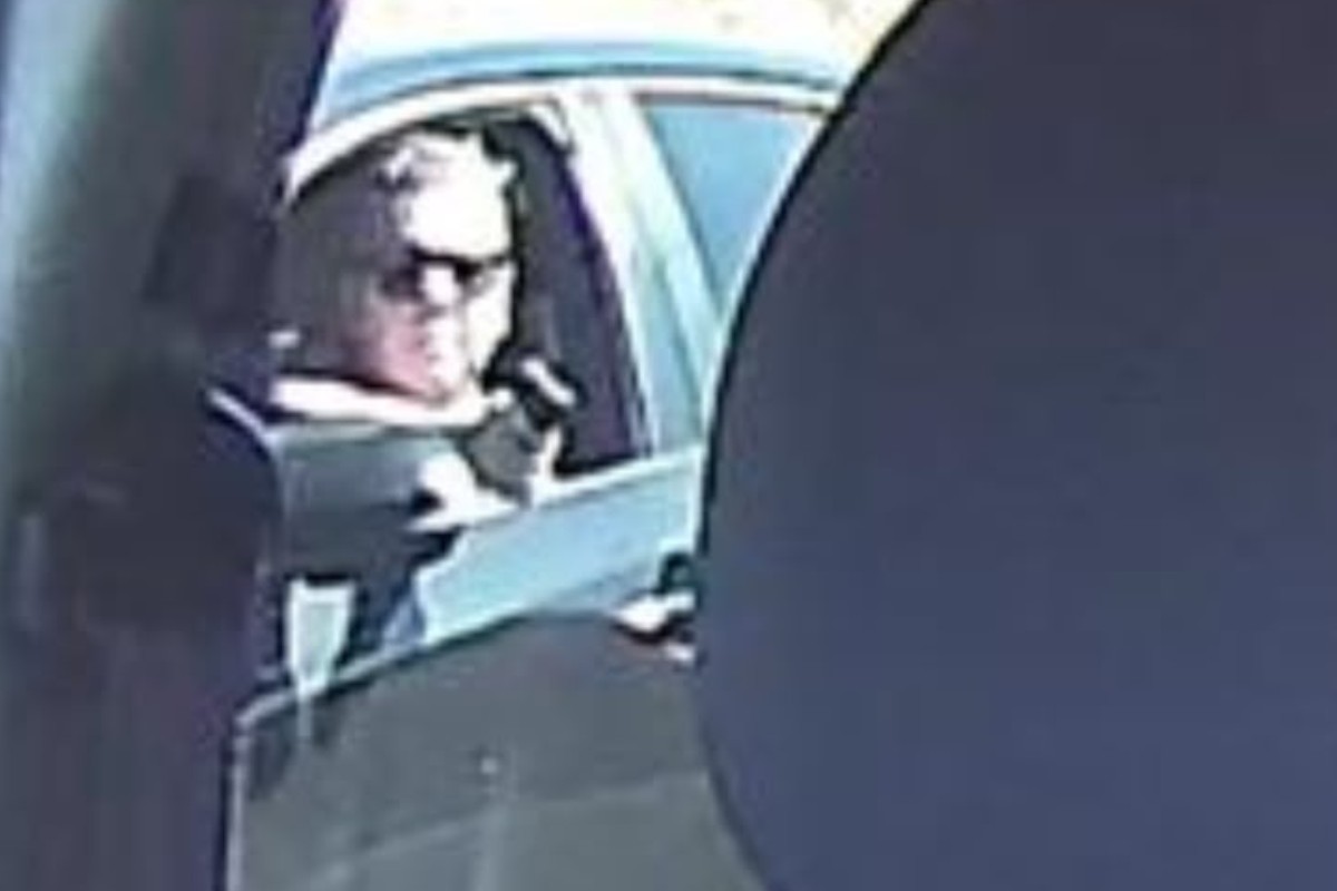 Homem aponta uma arma pela janela de carro preto na Rodovia Anhanguera