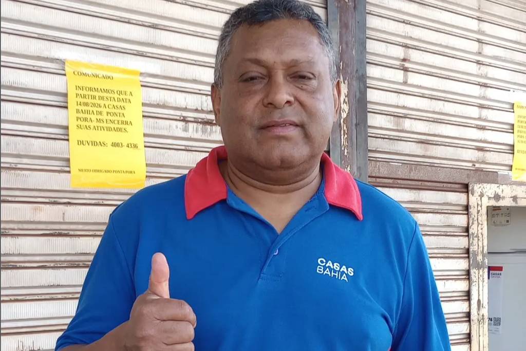 Edson Silva, ex-funcionário das Casas Bahia, diante de porta metálica fechada