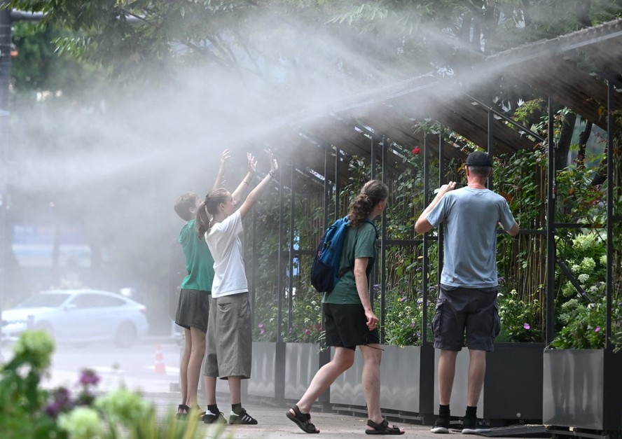 Pessoas se refrescam sob aspersores de água em rua de Seul