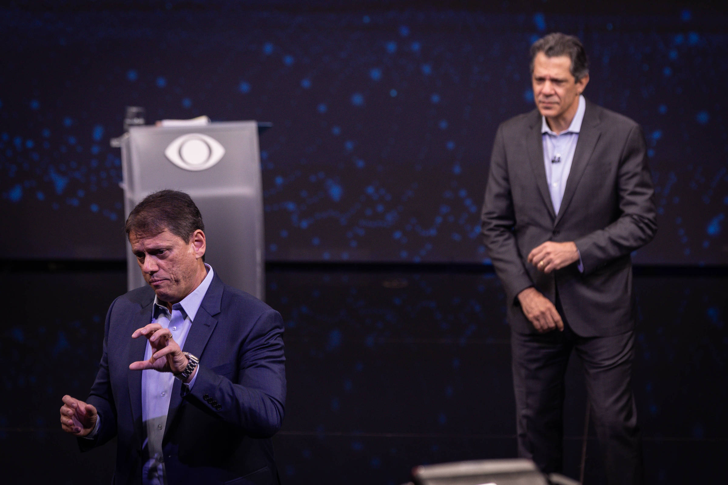 Tarcísio de Freitas à frente e Fernando Haddad ao fundo durante debate