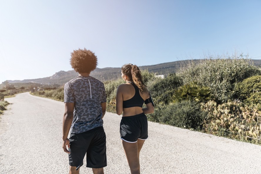Casal caminha junto por uma estrada