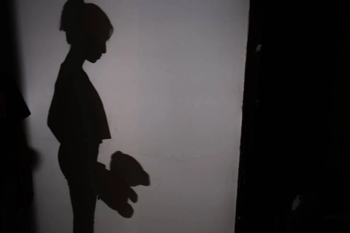Sombra de criança segurando um urso de pelúcia