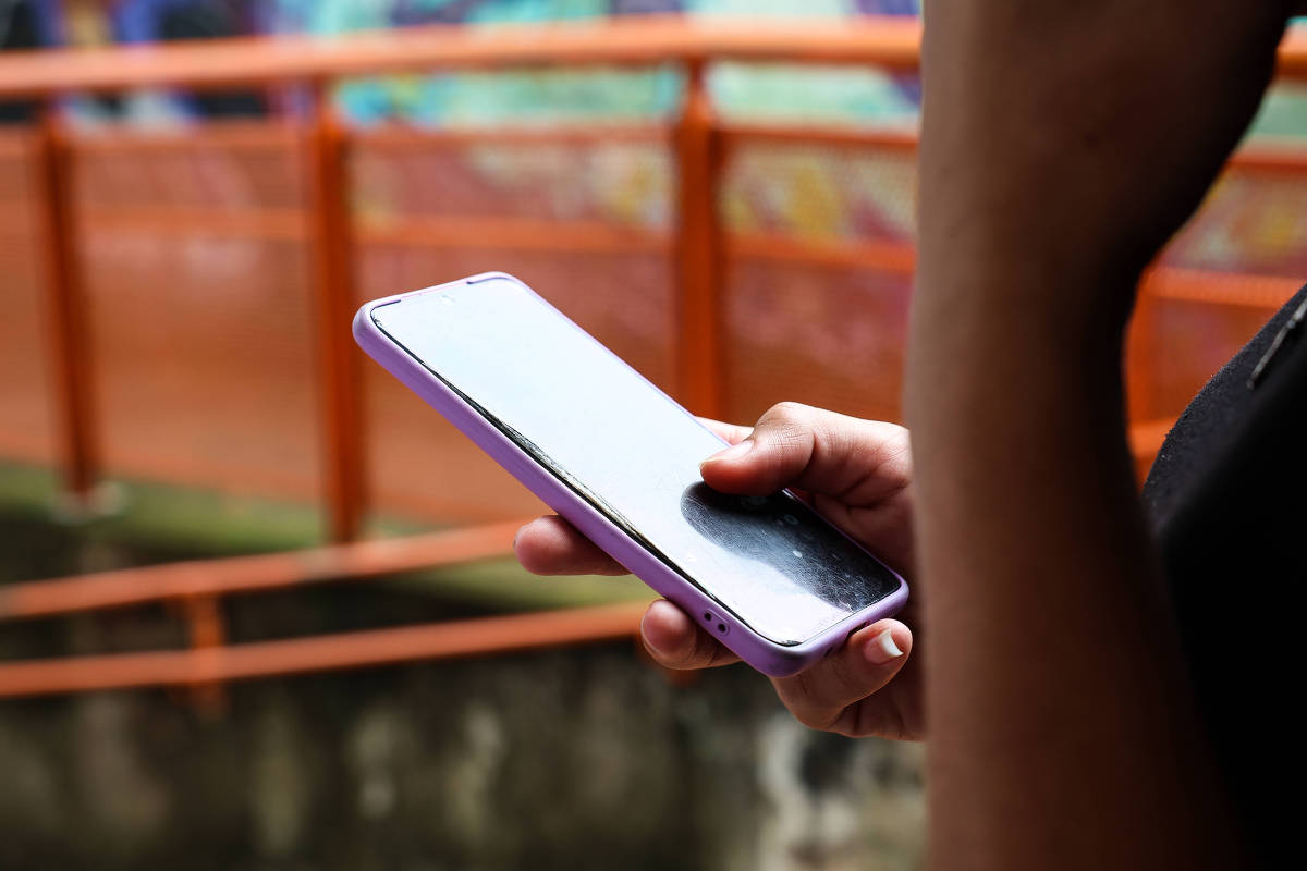 Estudante segura celular com capa roxa em escola de São Paulo