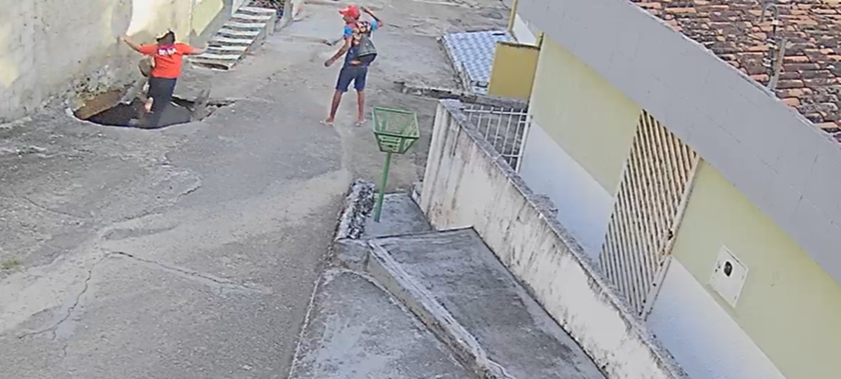 Mulher sentada com as pernas dentro de cratera em rua de Vitória de Santo Antão