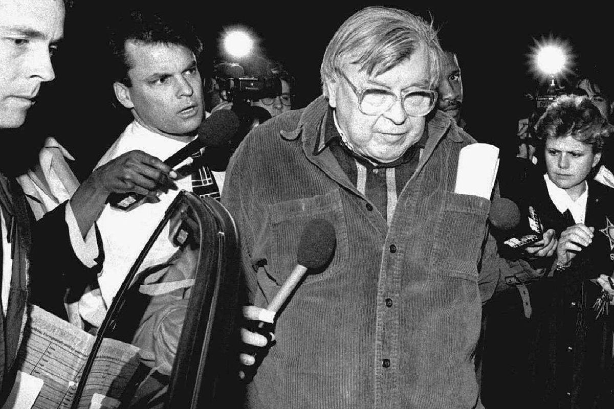 Daniel Carleton Gajdusek é escoltado por agentes do FBI