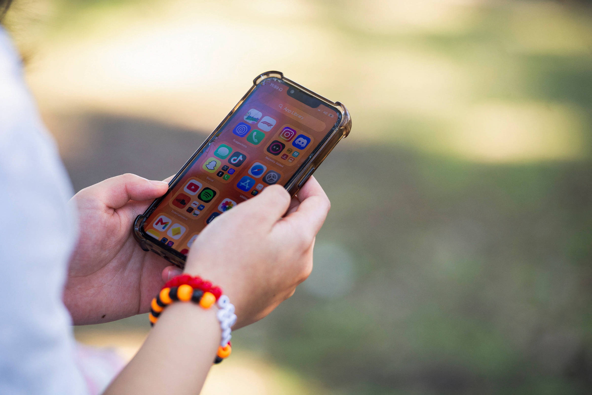 Jovem usa celular com aplicativos de redes sociais na tela