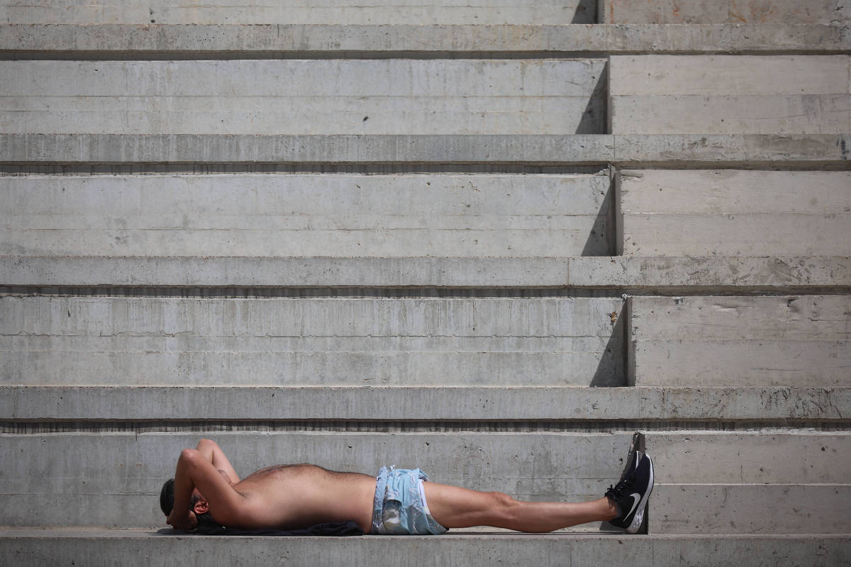 Homem toma sol em escadaria de concreto na praça Charles Miller, em São Paulo