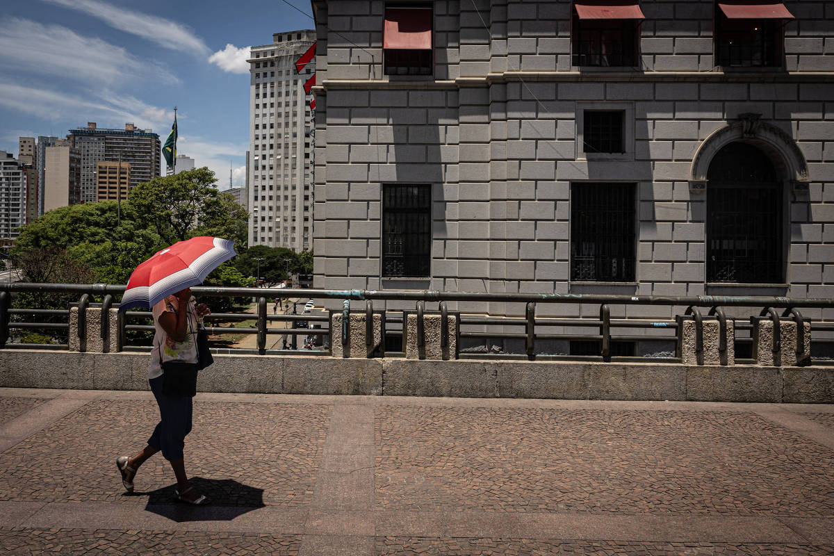 Mulher se protege do sol no Viaduto do Chá, em São Paulo