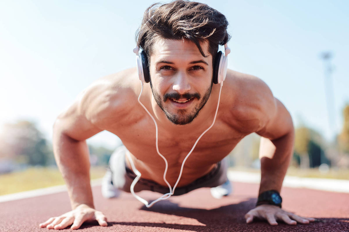 Homem faz flexões ao ar livre usando fones de ouvido