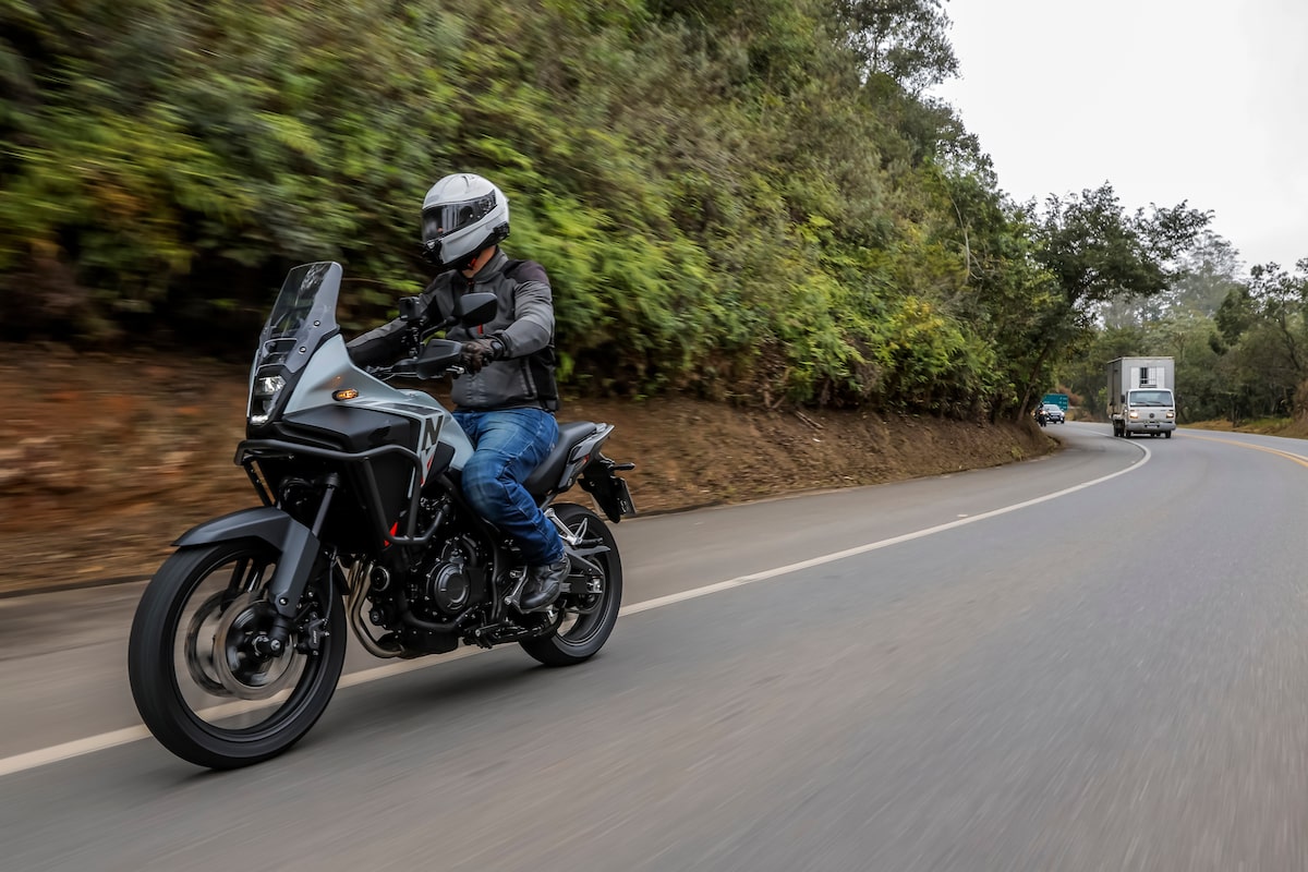 Motociclista trafega em rodovia perto de caminhões