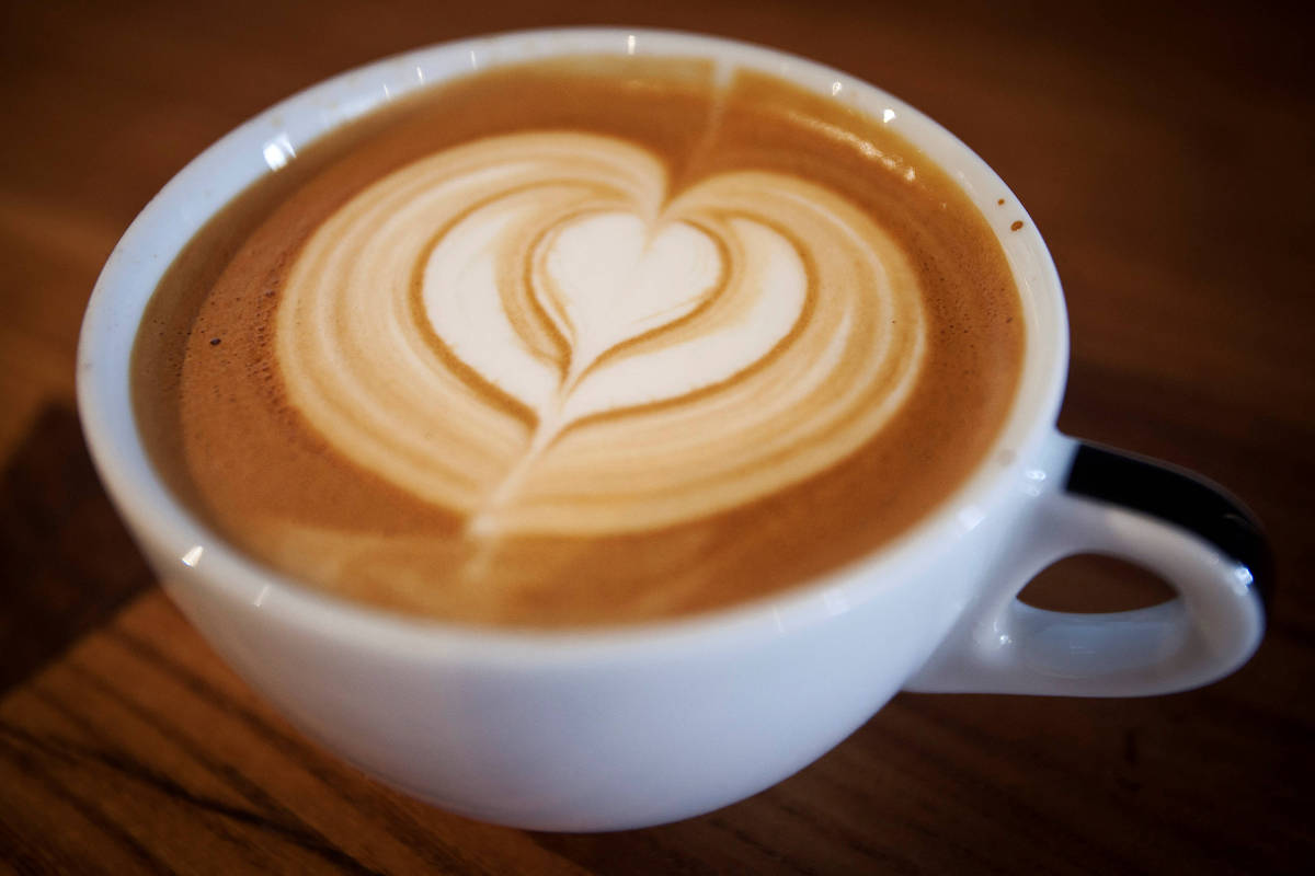 Xícara branca de cappuccino com desenho de coração na espuma