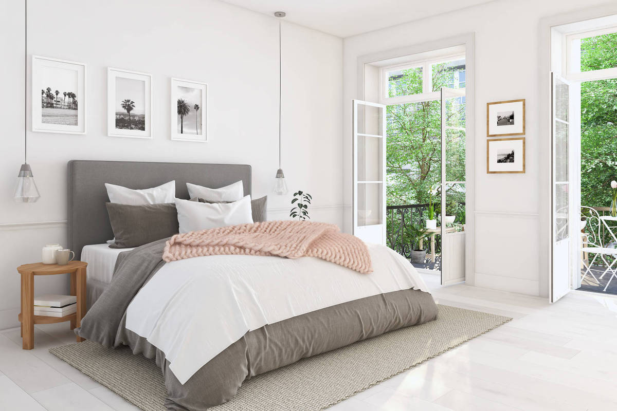 Quarto com cama, portas abertas e área verde ao fundo