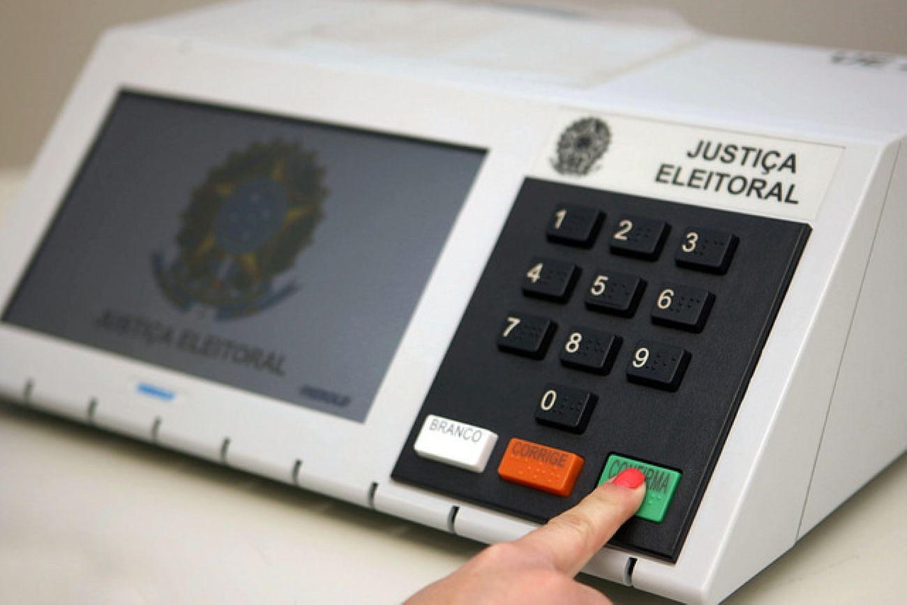 Mão de eleitora diante de urna eletrônica