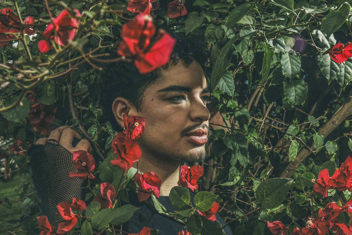 Matheus Daipre entre flores vermelhas e folhas verdes